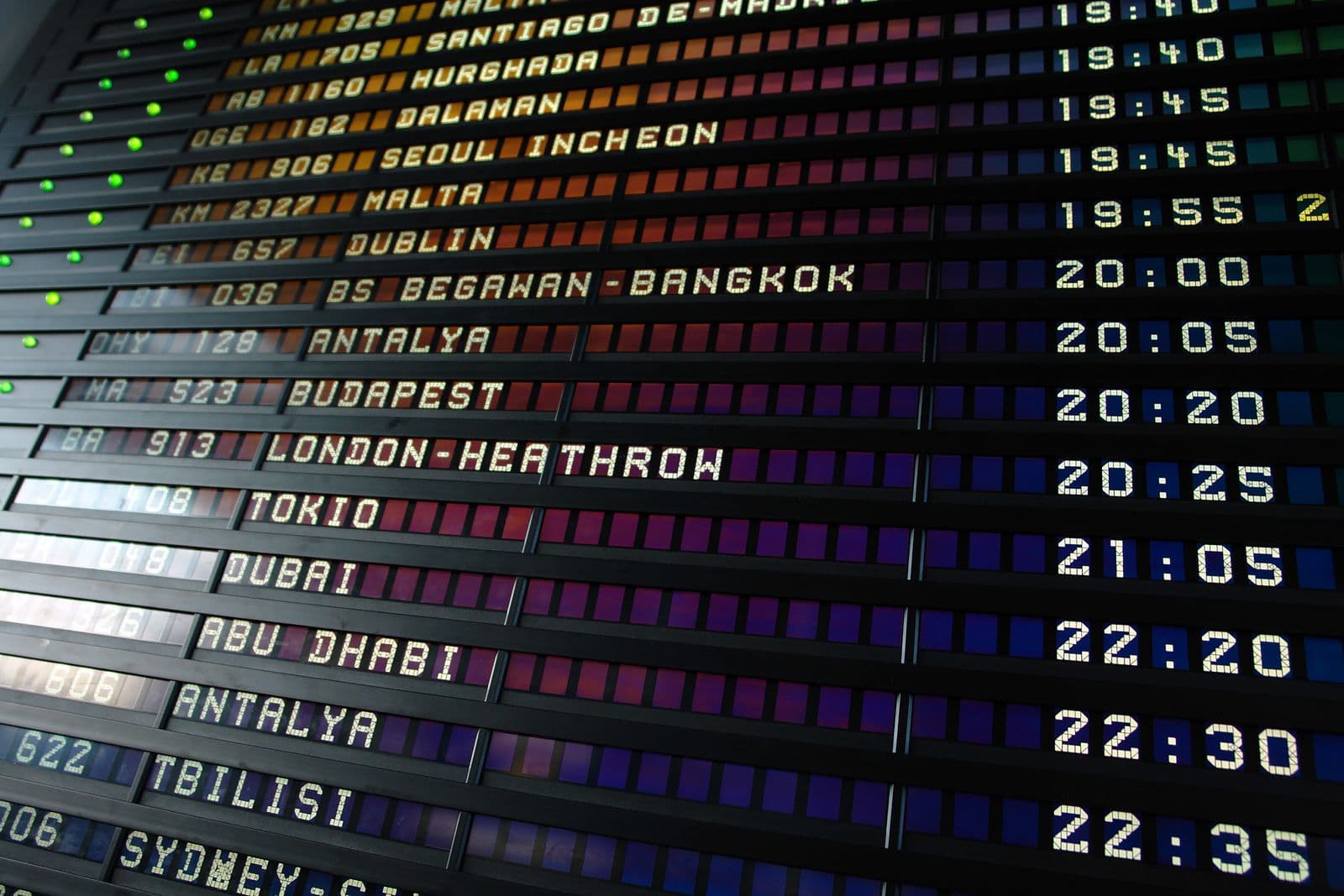 An airport split-flap departure board listing international flights and departure times